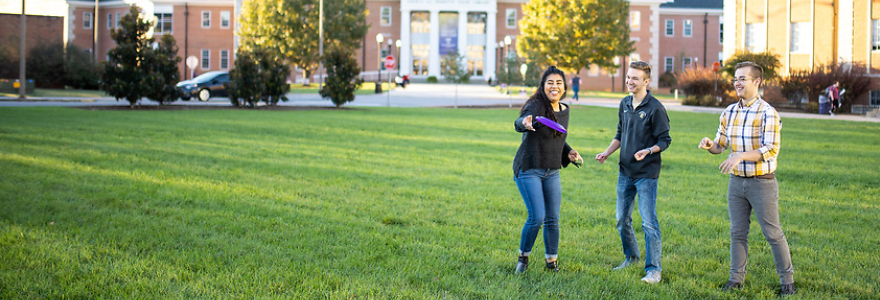 Students throwing a frisbee outside the Volpe Library. 