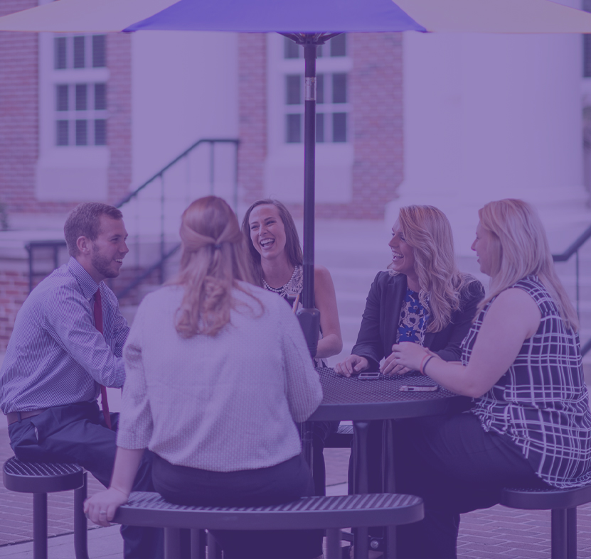 A group of business students chatting at an ourdoor table.