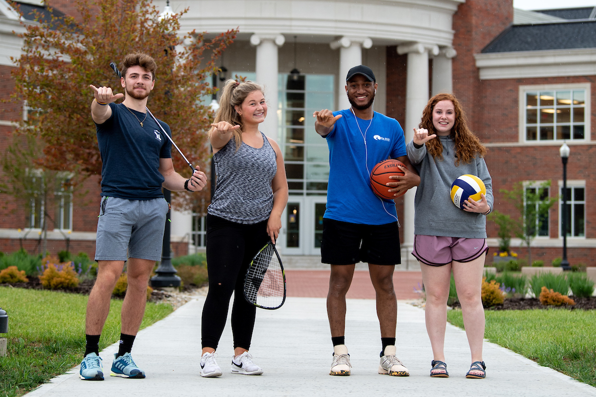 Students with recreational gear in front of the fitness center