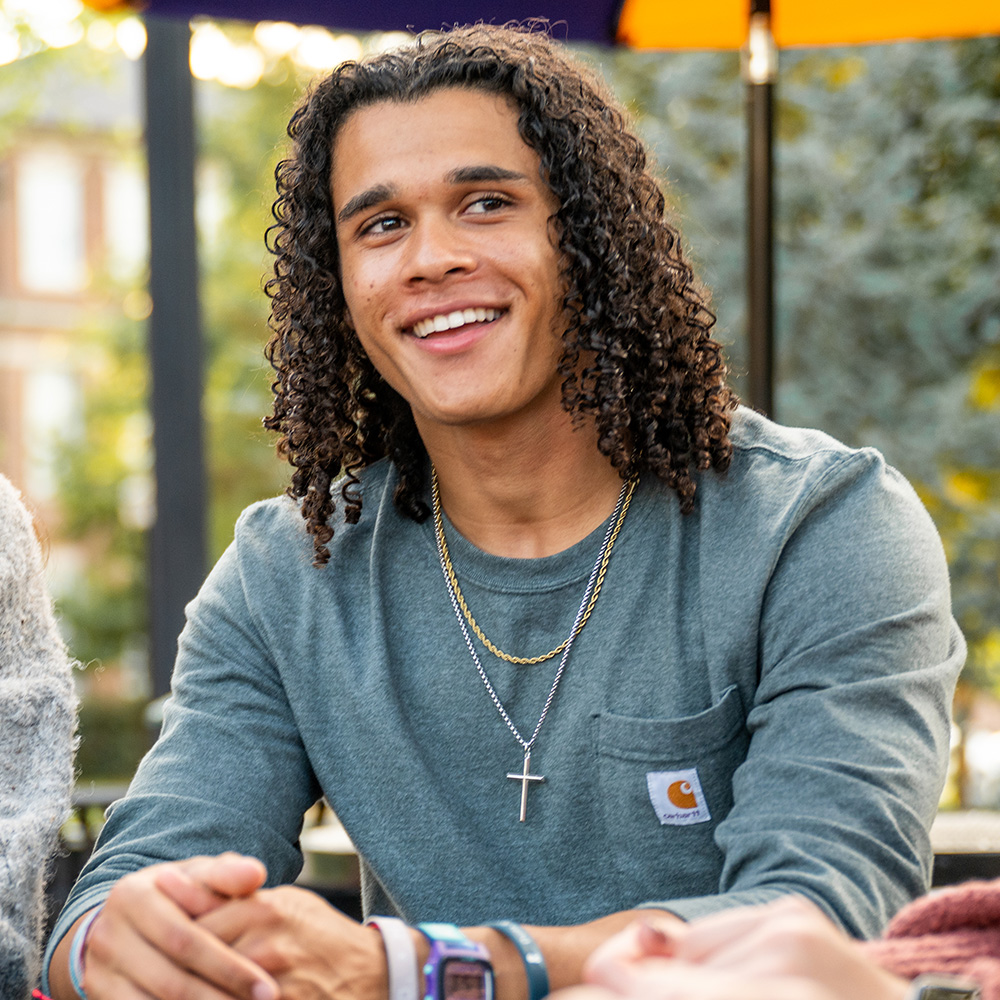 student smiling at an outdoor table